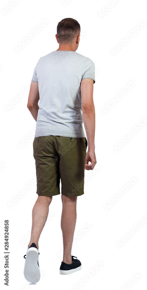 Fototapeta premium Back view of going handsome man in shorts.
