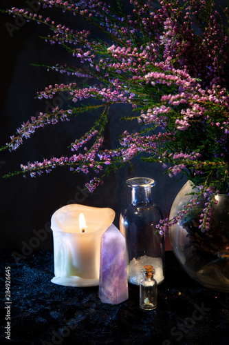 Flasks, crystal, candle and a bouquet of Heather. Mystical still-life.
