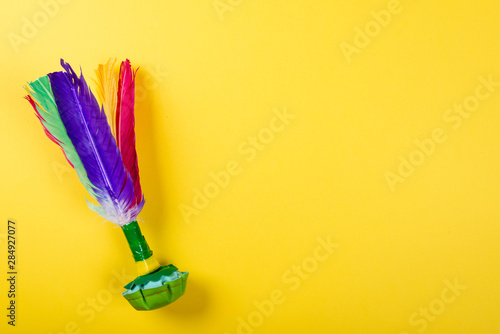 Shuttlecock with colorful feathers on yellow background. Space for text on the right side of the image.