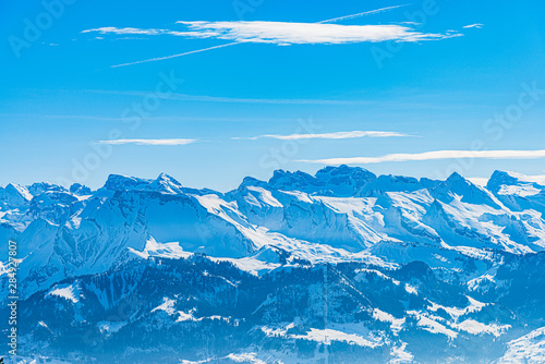 Majestic unique misty blue alpine skyline aerial view panorama of snowed Swiss Alps winter sports resort and blue sky. Mount Rigi Switzerland.