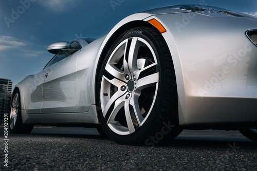 Modern luxury supercar front wheel rims. Silhouette of modern silver sportcar at the empty parking  