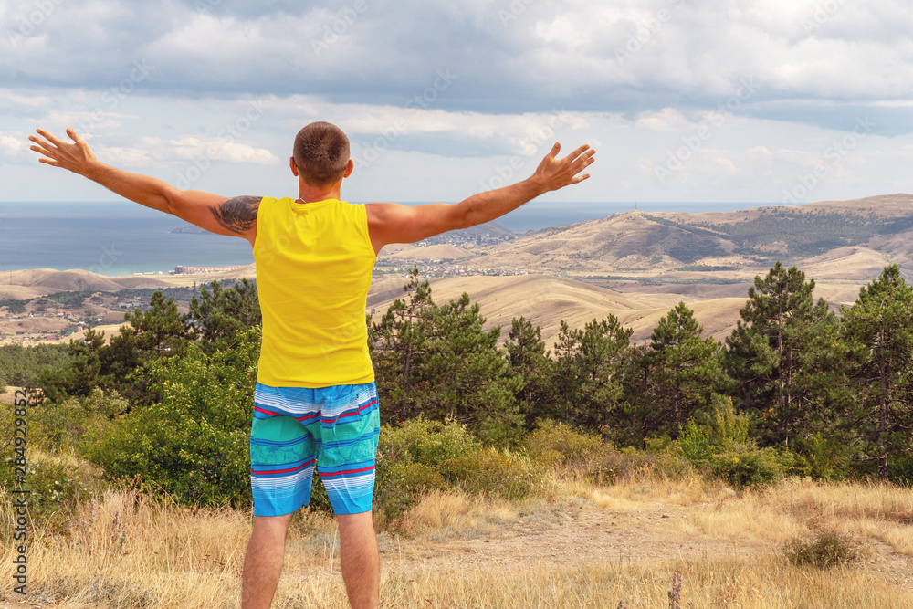 Man with arms outstretched and looking at the sea, mountains, nature