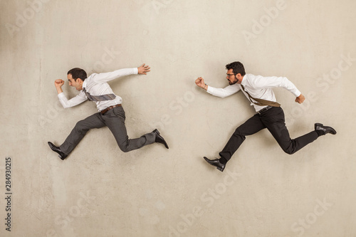 Businessmen chasing against beige background photo