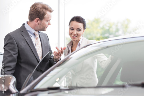 At the car dealer,Salesman showing new car to client photo