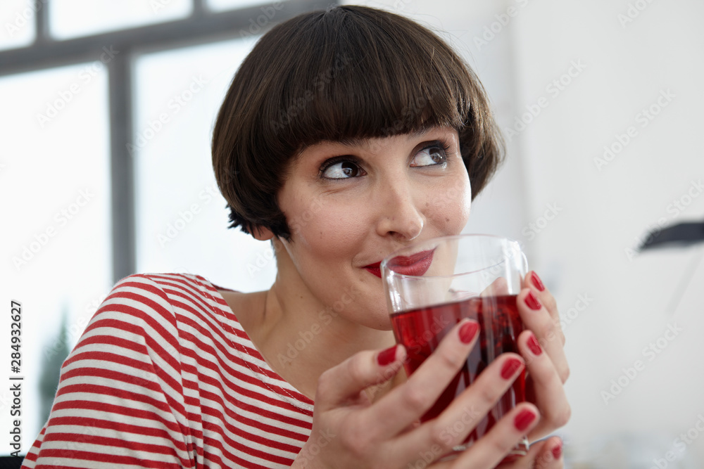 Germany, Cologne, Young woman sitting with glass of tea in apartment Germany, Cologne, Young woman sitting with glass of tea in apartment