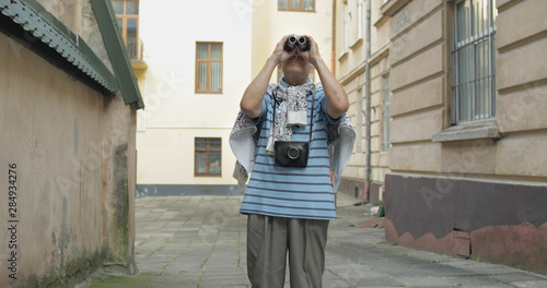 Senior man tourist exploring town. Looking in binoculars. Travel Lviv, Ukraine