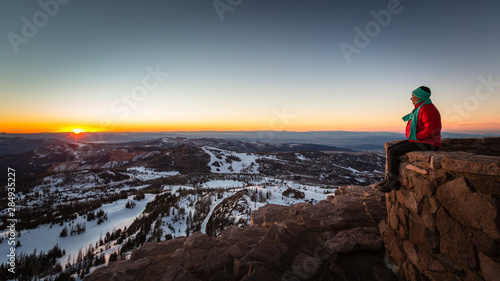 A woman sitting on a wall at forest service lookout at the summit of Brian Head, Utah.