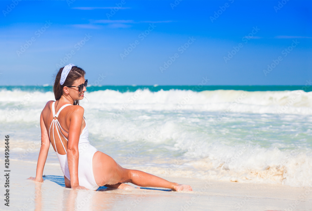 Young woman in bikini and straw hat relaxing at white caribbean beach Young woman in bikini and straw hat relaxing at white caribbean beach
