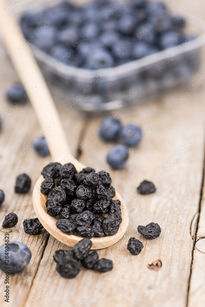Portion of Dried Blueberries on wooden background, selective focus Portion of Dried Blueberries on wooden background, selective focus