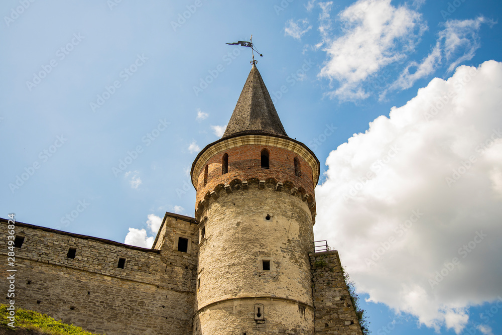 ancient medieval castle tower and stone wall on blue sky with white clouds background, copy space 