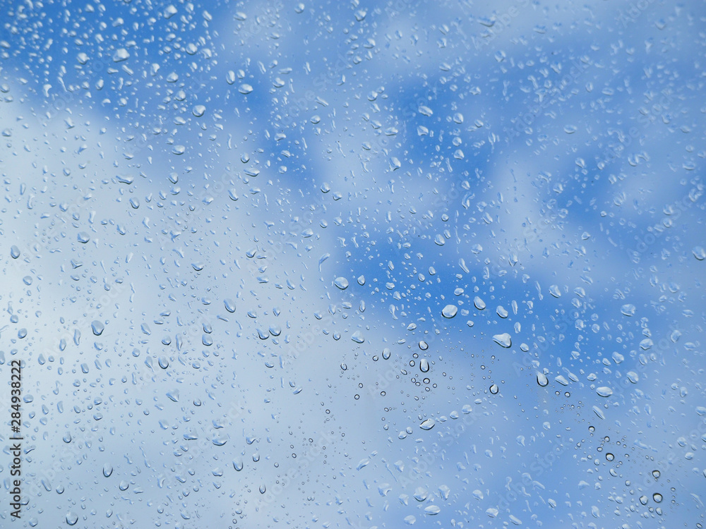Raindrops on glass blue sky background.