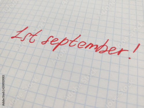 Handwritten inscription in felt-tip pen on the first of september on squared paper. Preparation for school, the beginning of the school year, September 1, a sheet in a cage