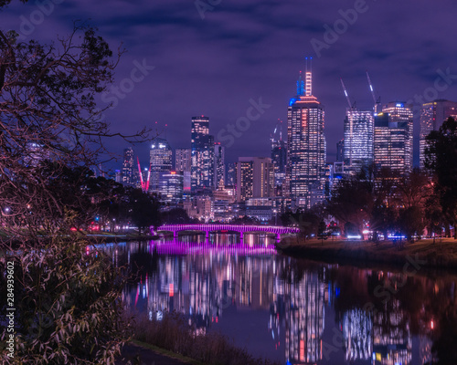Melbourne Skyline at night with magenta lit bridge in foreground