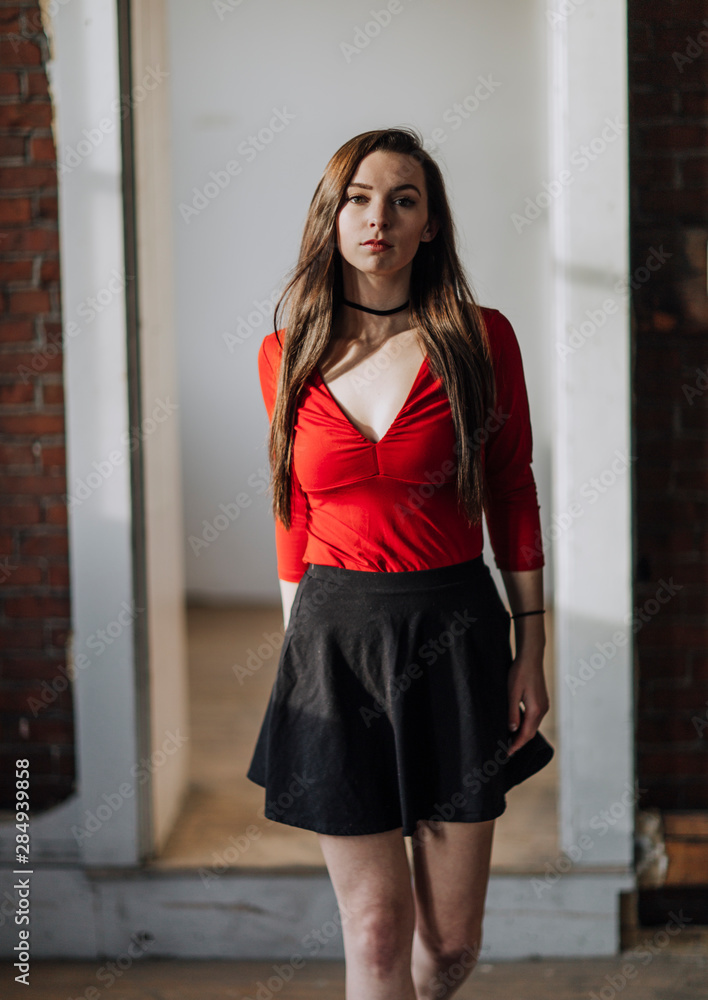 A young woman wearing a red shirt and black skirt walks directly at me  Stock Photo | Adobe Stock