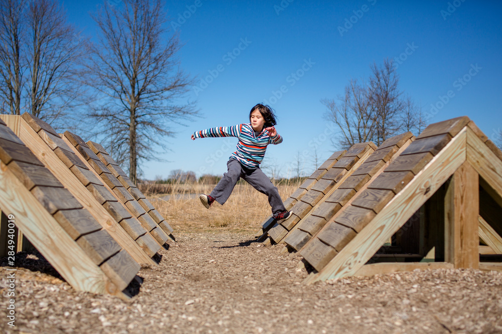 Portrait of a child mid-leap jumping across an obstacle course in park Portrait of a child mid-leap jumping across an obstacle course in park