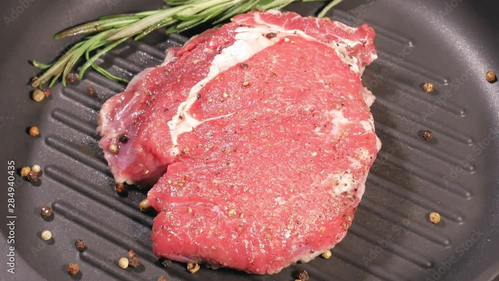 The meat steak is fried with a leaf of rosemary and peppercorns in a slowly rotating pan. Cooking ribeye top view. Carefully selected products. Classic veal cooking. The meat steak is fried with a leaf of rosemary and peppercorns in a slowly rotating pan. Cooking ribeye top view. Carefully selected products. Classic veal cooking.