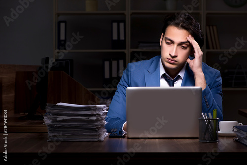 Young male employee working night in the office