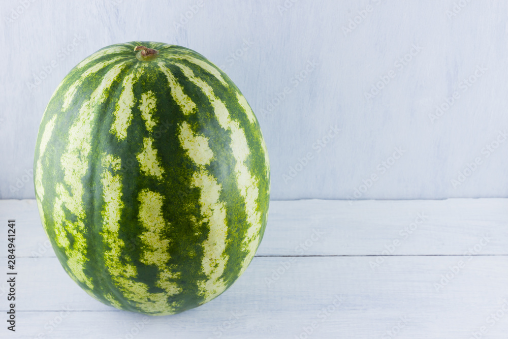Watermelon on natural white background. Whole watermelon on wooden background. Healthy food for vegan. Copy space Watermelon on natural white background. Whole watermelon on wooden background. Healthy food for vegan. Copy space
