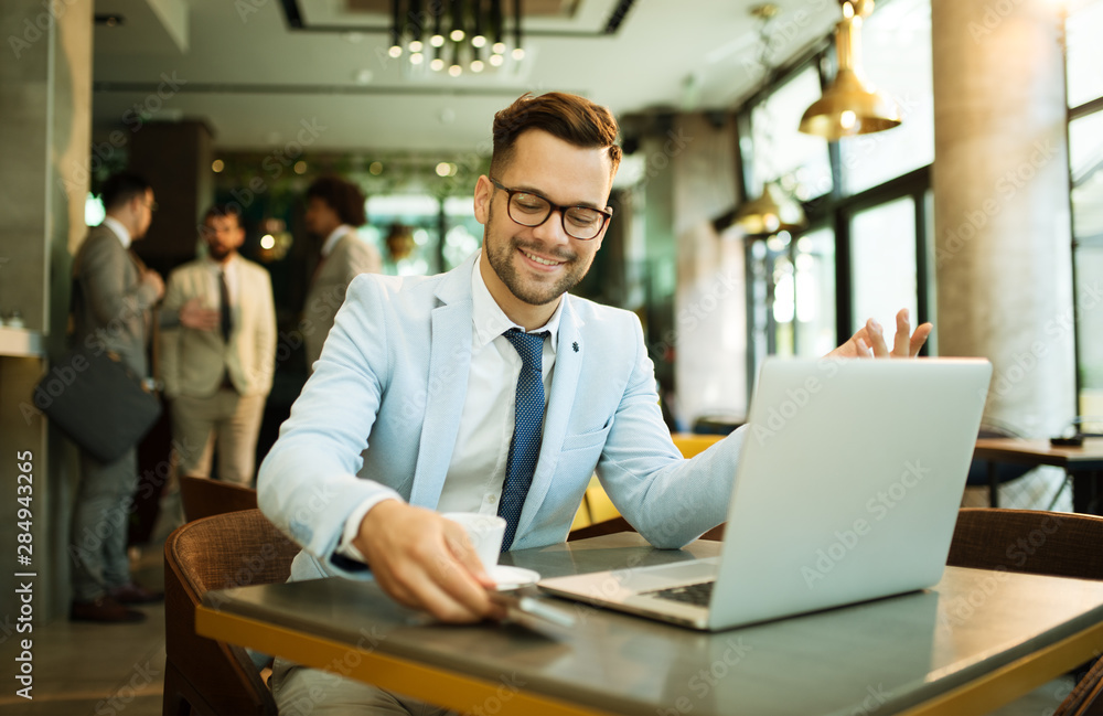 Fototapeta premium Young businessman uses a laptop in a cafe