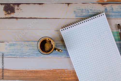 Notepad with pen and espresso coffee on table.