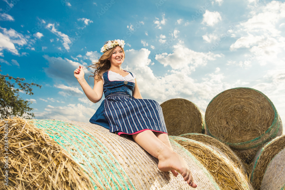 Bayerische Frau im Dirndl auf einem strohballen Oktoberfest Theme