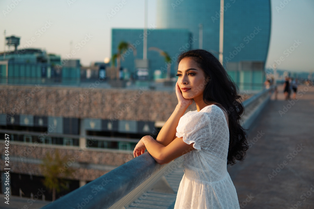 Beautiful girl in the white dress waiting along the sea promenade. Elegance and tenderness concept Beautiful girl in the white dress waiting along the sea promenade. Elegance and tenderness concept
