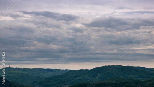 The panoramic mountain scenery with television tower(Buková hora) to the left on the horizon and dark cloudy sky.