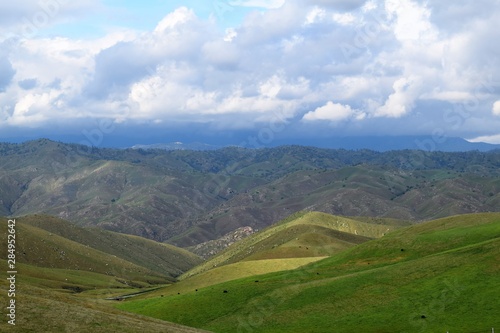 Colorful Rolling Hills with Background Mountains and Cloudy Gray-Blue Skies