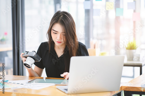 Young Asian graphic designer working on computor and graphics tablet in her working space