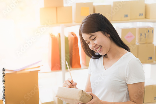 Asian freelance woman working at home and start up small business entrepreneur SME with internet online. woman is preparing the goods in the package box to prepare the delivery for the customer.