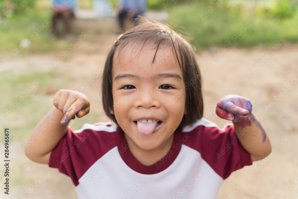 Little girl shows the tongue and hands smearing the color from learning art. Little girl shows the tongue and hands smearing the color from learning art.