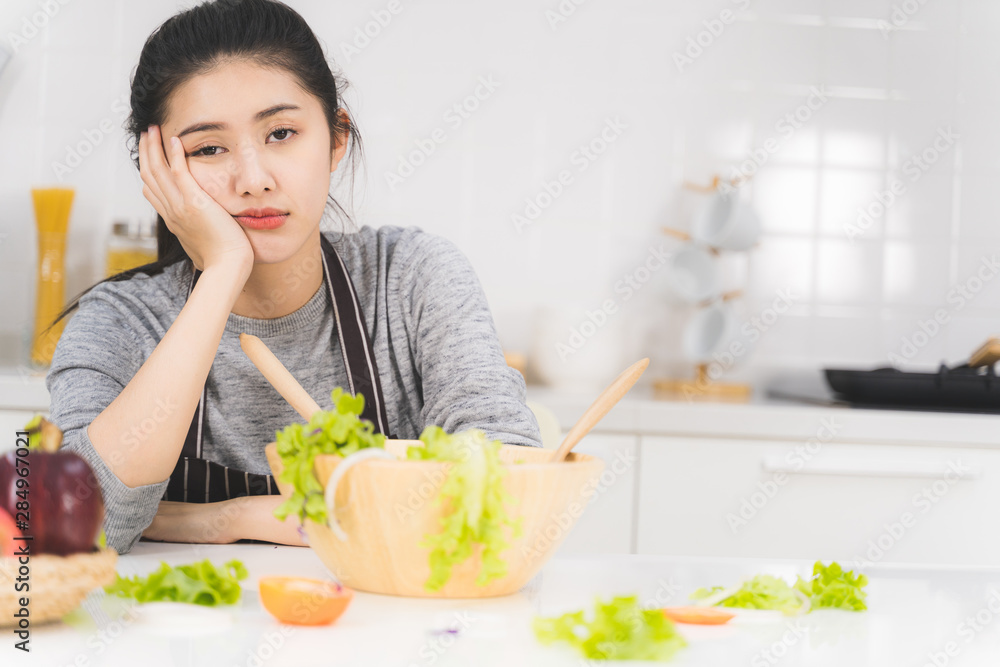 Young woman or housewife is bored of cooking, which consists of a variety of fruits and vegetables for the family.