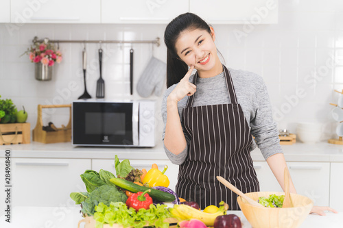 Portrait of pretty asian woman in the bright white kitchen. wife or housewife is preparing to cook healthy food which consists of a variety of fruits and vegetables for the family.