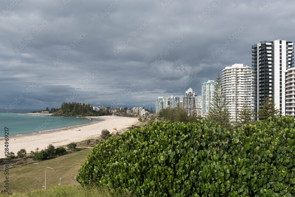 Elevated view of Coolangatta and Greenmount Beaches backed by the high-rises of Coolangatta, under a grey, cloudy sky. Coolangatta, Gold Coast, Queensland, Australia.
