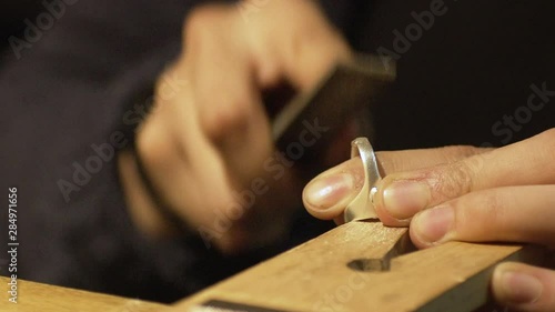 Jeweller files away at ring at his workbench