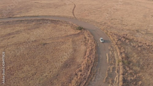 AERIAL shot of drone following a car around a old abandoned race track