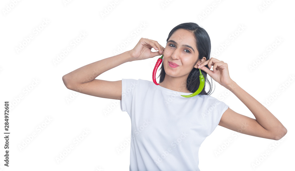 Young brunette indian girl holding red and green pepper chili with her fingers isolated on white, playing with food concept Young brunette indian girl holding red and green pepper chili with her fingers isolated on white, playing with food concept