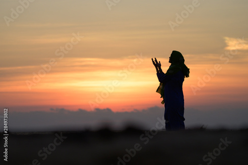 Muslim Girl saying prayer by the beach with sunset © Sharpnaja