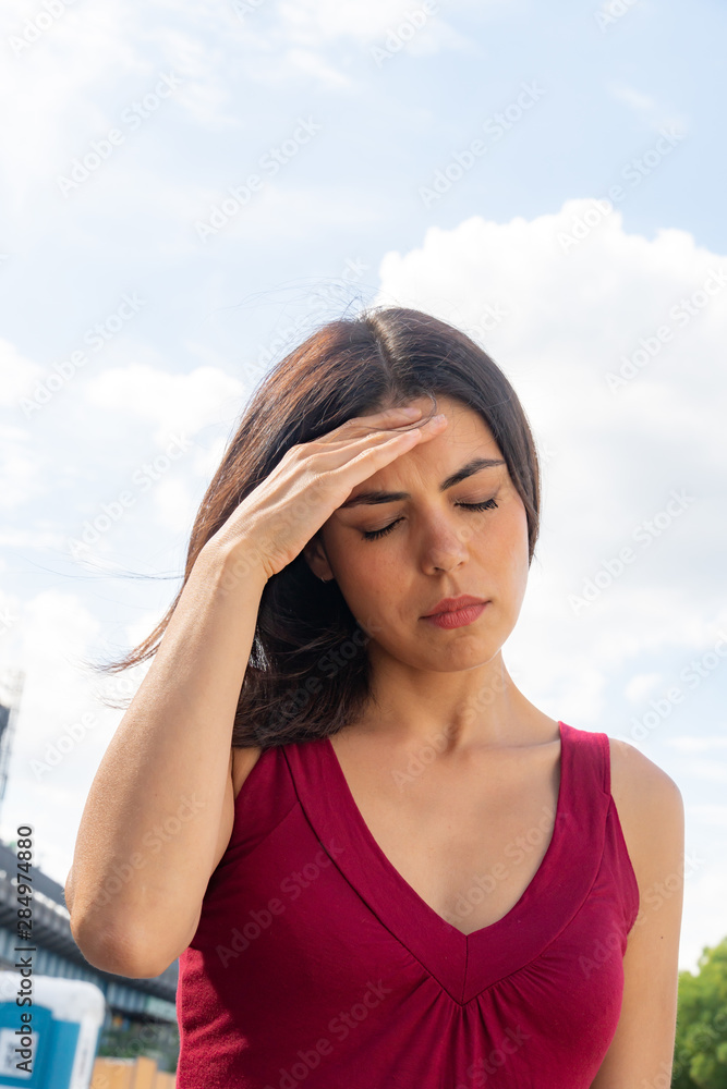 Close up portrait of a brunette woman dealing with an awful dizzy spell. Outdoors