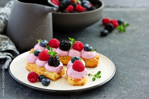 Homemade eclair with berry cream and fruits. . Pastry.