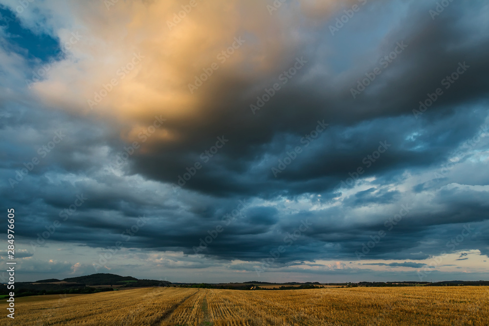 Blue cloudy dramatic sky with mowed field and hill, Czech republic Blue cloudy dramatic sky with mowed field and hill, Czech republic