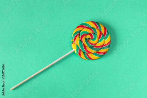 Multicolore lollipop swirl on wooden stick on a green background