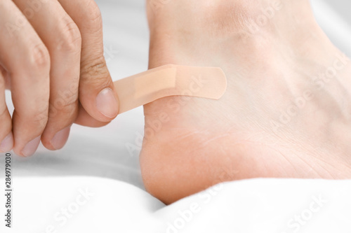 Man applying adhesive bandage on heel indoors, closeup © New Africa