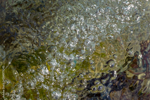 Background of greenish transparent water with air bubbles on the surface.