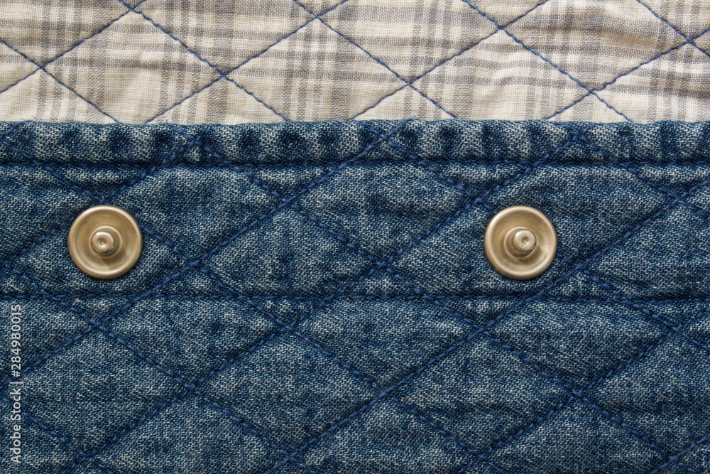 Quilted fabric denim cloth element texture close up with metal buttons Quilted fabric denim cloth element texture close up with metal buttons