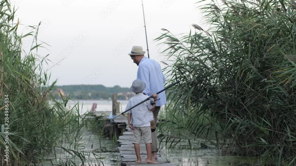 relationship father son, loving parent leads his cute little boy to fish on pier near river during family leisure at summer relationship father son, loving parent leads his cute little boy to fish on pier near river during family leisure at summer