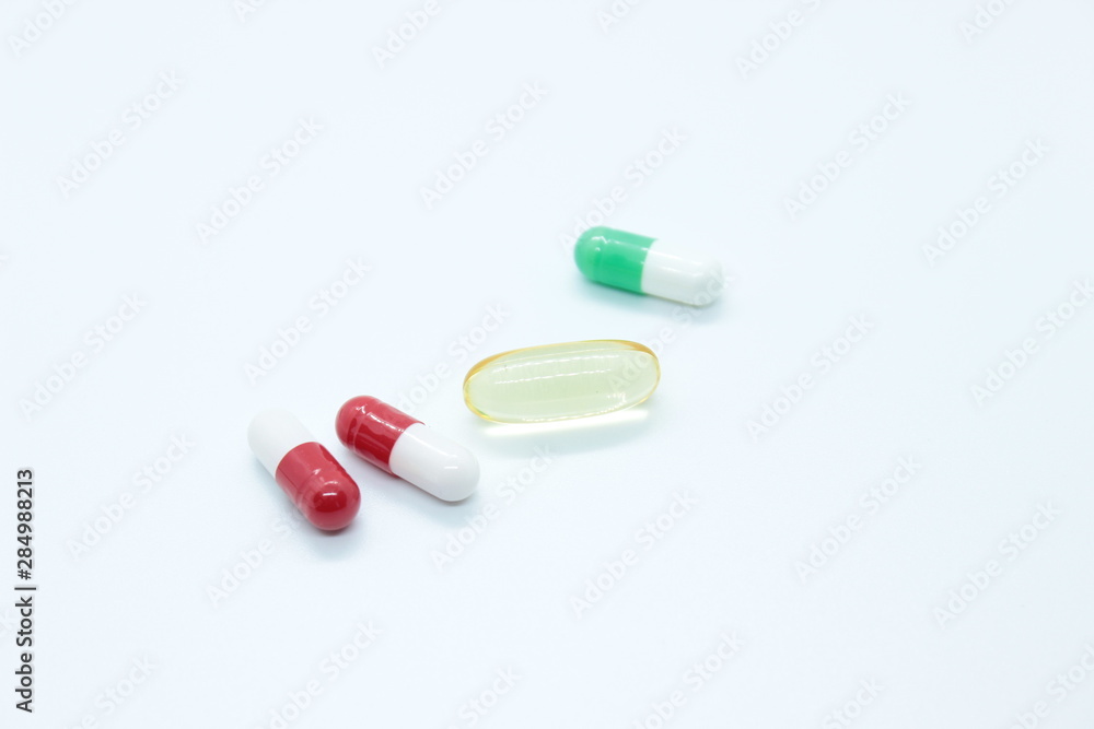 Multi-colored pill capsules are located on a white background Multi-colored pill capsules are located on a white background