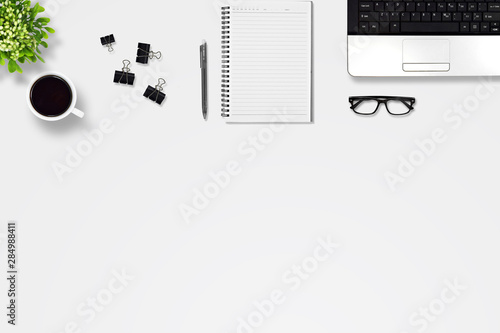 Top view office desk with laptop, pen, notebook, paper clip, glasses, Flower vase, coffee, supplies, with copy space background. Creative flat lay photo of workspace desk