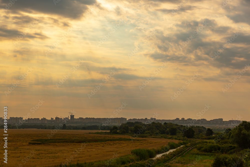 The slanting rays of the sun in the pre-dawn sky illuminate the countryside against the urban background. The slanting rays of the sun in the pre-dawn sky illuminate the countryside against the urban background.