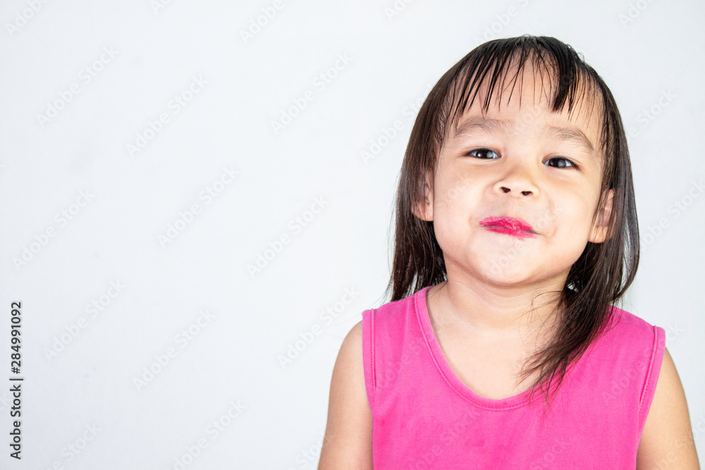 Happy Asian child girl with apply red lipstick wearing pink dress isolated on white background. Happy Asian child girl with apply red lipstick wearing pink dress isolated on white background.